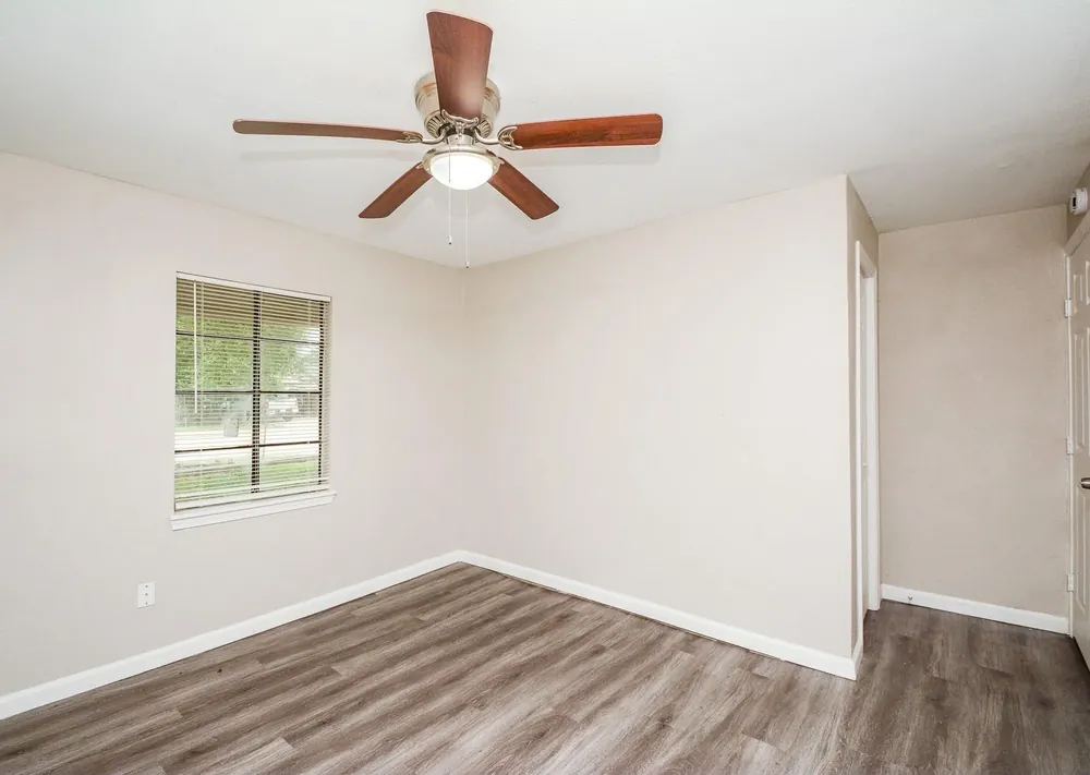 Bright clean bedroom with ceiling fan and new flooring